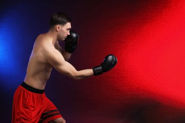 Boks eldivenli adam karanlık arka planda neon ışıklarda dövüşüyor, metin için yer var.