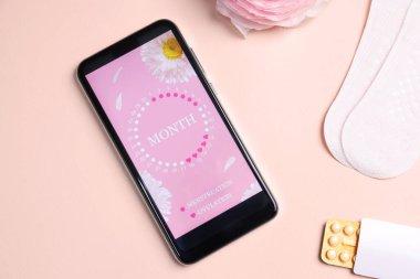 Dönem takvimi uygulamalı akıllı telefon, regl ürünleri ve bej arka planda çiçek, düz uzanma