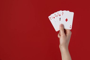 Kırmızı arka planda iskambil oynayan kadın, yakın plan. Metin için boşluk