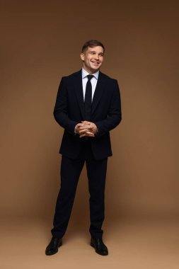 Kahverengi arka planda klasik takım elbiseli adam.