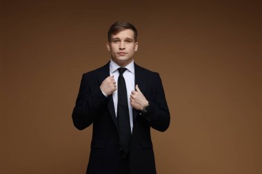 Kahverengi arka planda klasik takım elbiseli adam.