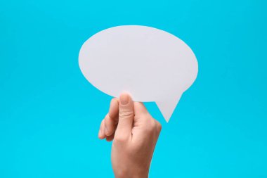 Açık mavi arka planda boş konuşma balonu tutan kadın, yakın plan. Metin için boşluk