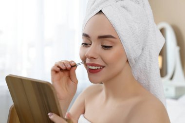 Mutlu kadın evde cımbızla bıyığını koparıyor.