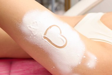 Güzellik salonunda tüy dökme işleminden sonra bacağına nemlendirici losyon sürmüş bir kadın.