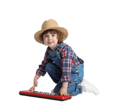 Beyaz arka planda oyuncak elektrikli piyano çalan sevimli bir çocuk.