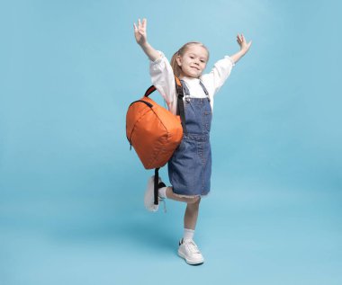 Açık mavi arka planda sırt çantası olan tatlı bir kız öğrenci.