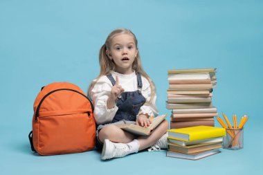 Sırt çantası ve açık mavi arka plan kitapları olan liseli kız.