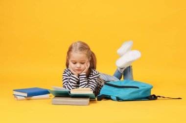 Sırt çantalı, sarı arka plan kitapları okuyan tatlı bir kız öğrenci.