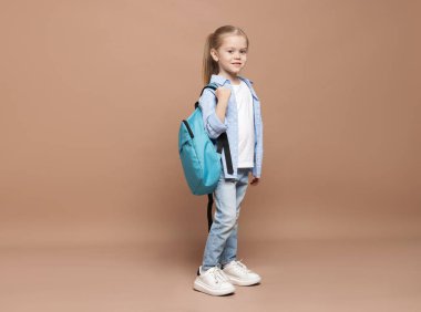 Kahverengi arka planda sırt çantası olan tatlı bir kız öğrenci.