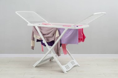 Gri duvarın yanında temiz çamaşırları olan kuru askı.