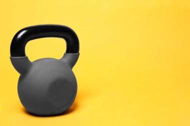 Sarı arka planda ağır bir kettlebell. Metin için boşluk