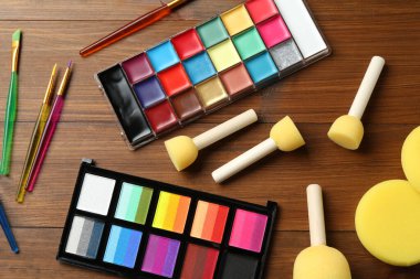 Ahşap zemin üzerinde yüz boyaları ve araçlar düz yatıyordu.