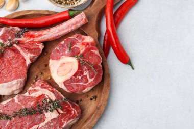 Çiğ et, baharat ve kırmızı biber parçaları açık gri masada, düz yerde. Metin için boşluk