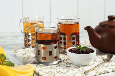 Beyaz masada servis edilen metal tutacaklı çay bardakları.