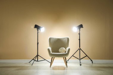 Profesyonel ışıklandırma ekipmanları ve fotoğraf stüdyosunda dekoratif yastıklı koltuk.