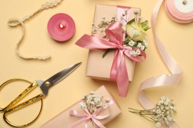 Çiçekçi. Kutular, çiçekler, kurdele, yanan mum ve makas bej arka planda, düz konum
