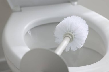 Cleaning toilet bowl with brush indoors, closeup
