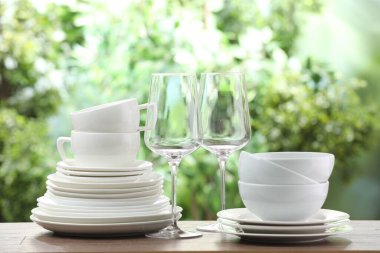 Clean dishware on wooden table against blurred background