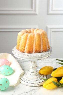 Lezzetli kek, Paskalya yumurtası ve beyaz mermer masada laleler.