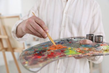 Sanatçının stüdyosunda boyaları palette karıştıran adam, yakın plan.