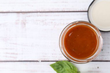 Cam kavanozda köri sosu ve beyaz ahşap masada fesleğen. Metin için boşluk