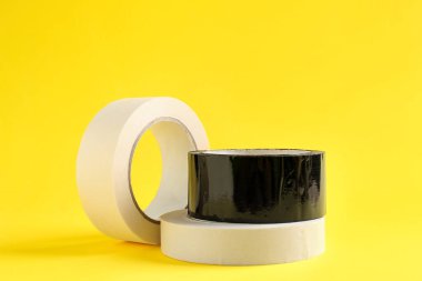 Sarı arka planda farklı yapışkan bantların ruloları