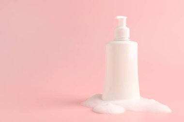 Pembe arka planda köpüklü bir şişe kozmetik ürünü, metin için boşluk