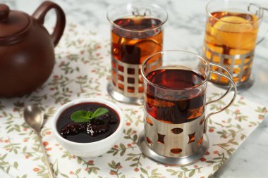 Beyaz masada servis edilen metal tutacaklı çay bardakları.