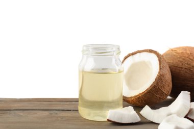 Coconuts and cooking oil on wooden table against white background