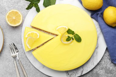 Tasty lemon cheesecake, mint and citrus fruits on grey textured table, flat lay