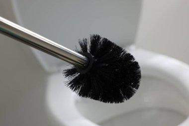 Black toilet brush and bowl indoors, selective focus