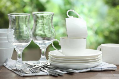 Clean dishware on wooden table against blurred background