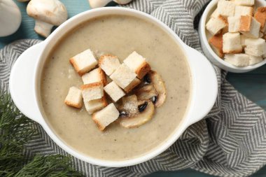 Lezzetli mantar kremalı çorba, kızarmış ekmek ve malzemeler mavi masada.