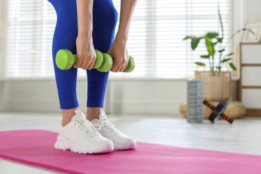 Evde dambıllarla egzersiz yapan bir kadın, yakın plan. Metin için boşluk