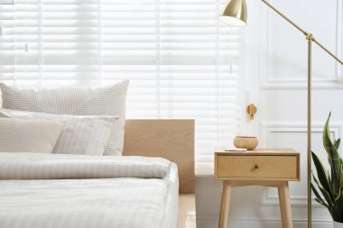 Rahat bir yatak ve şık bir odada komodin, yakın plan. İç tasarım