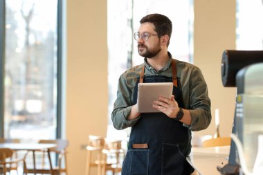 Kafesinde tabletle çalışan yakışıklı bir işletme sahibi. Metin için boşluk