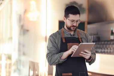Kafesinde tabletle çalışan yakışıklı bir işletme sahibi. Metin için boşluk