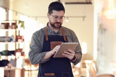 Kafesinde tabletle çalışan yakışıklı bir işletme sahibi.