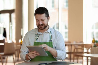 Kafesinde tabletle çalışan yakışıklı bir işletme sahibi.