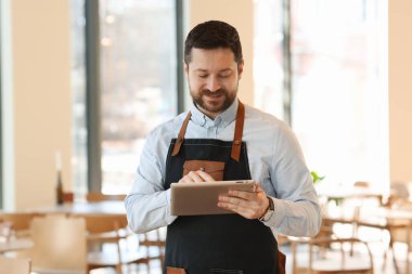 Kafesinde tabletle çalışan yakışıklı bir işletme sahibi.