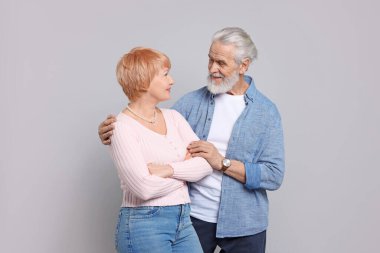 Gri arka planda poz veren sevimli yaşlı çift.