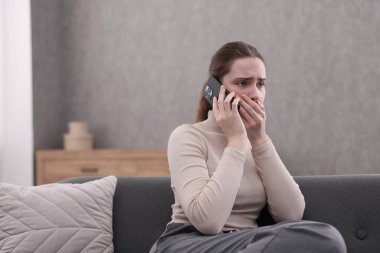Depresyondaki kadın evdeki kanepede ruh sağlığı için yardım hattını arıyor.