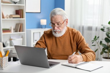 Üst düzey adam içeride masa başında öğrenirken not alıyor. Kendi kendine çalışma.