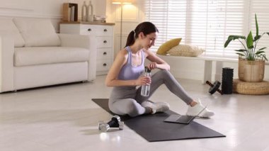 Spor giyim bölümünde dizüstü bilgisayarla video dersi izleyen bir kadın.