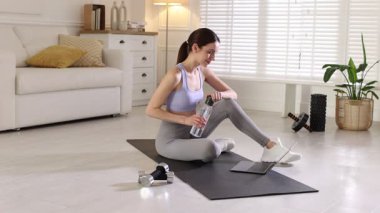 Spor giyim bölümünde dizüstü bilgisayarla video dersi izleyen bir kadın.