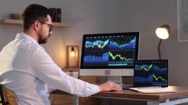 Borsa. Kapalı alandaki bilgisayarda finansal piyasayı analiz eden adam.