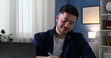 Kendi kendine çalışma. İçerideki masada ders sırasında not alan bir adam. Kamera aşağı iniyor