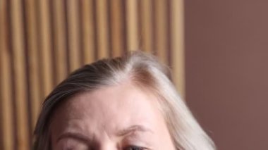 Kıdemli kadın saç köklerine masaj yapıyor arka planda bulanık, yakın plan. Kamera yakınlaştırılıyor