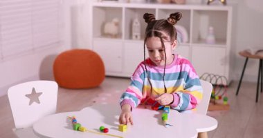 Oyun masasında iplik oyuncağıyla oynayan sevimli küçük kız.