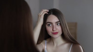 Evinde aynanın yanında sağlıklı saç kökleri olan güzel bir kadın.